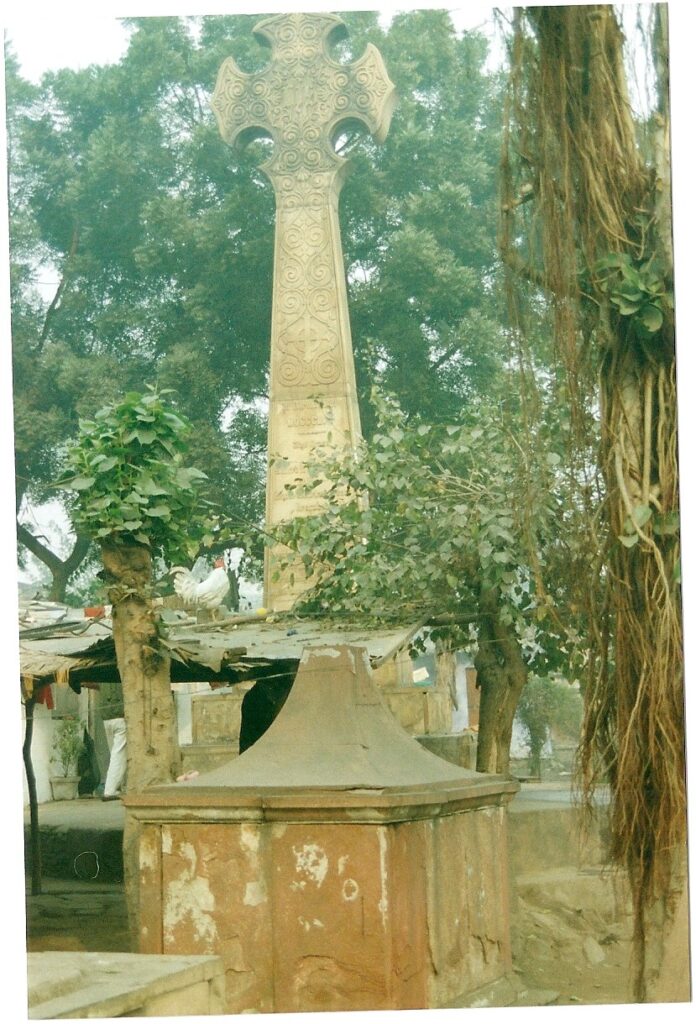 Very tall stone cross looking down on ramshackle grave.