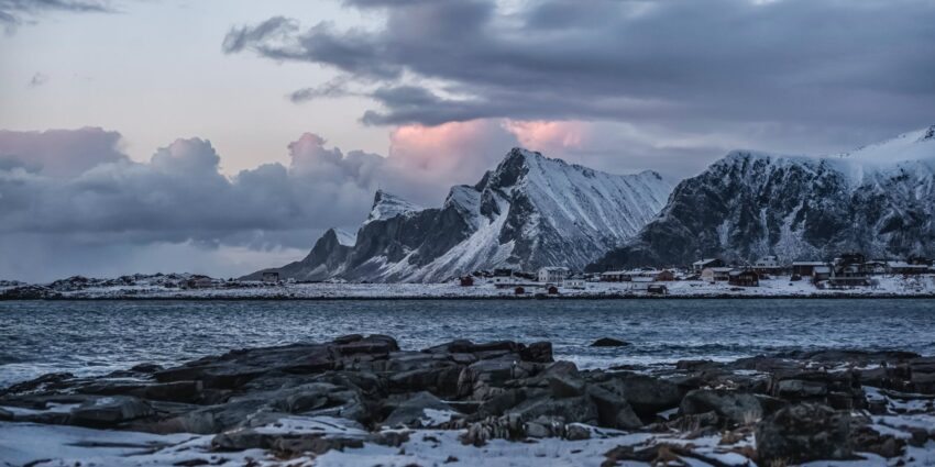 rocky mountain near body of water under cloudy sky