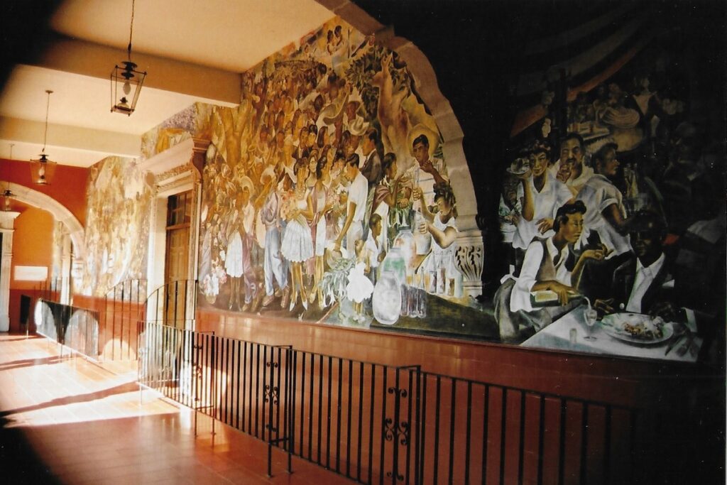 Mural strewn first floor walls of the municipal town hall. They paint vivid historic and local Mexican scenes. 