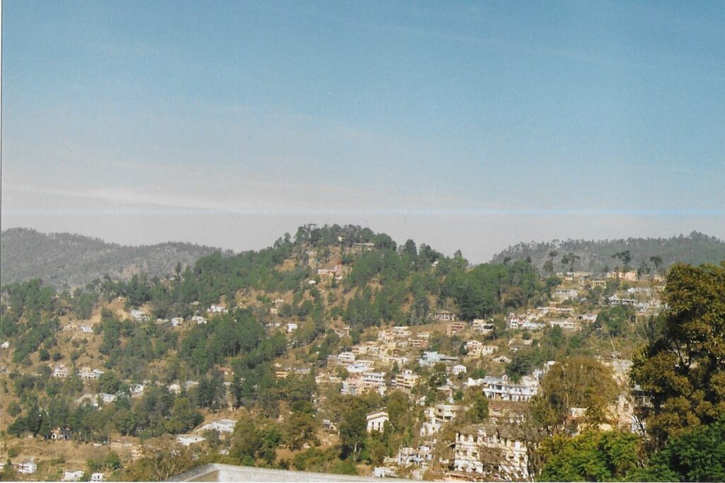 Visit Nainital. Houses rise up in terraces against the side of a Nainital hill.