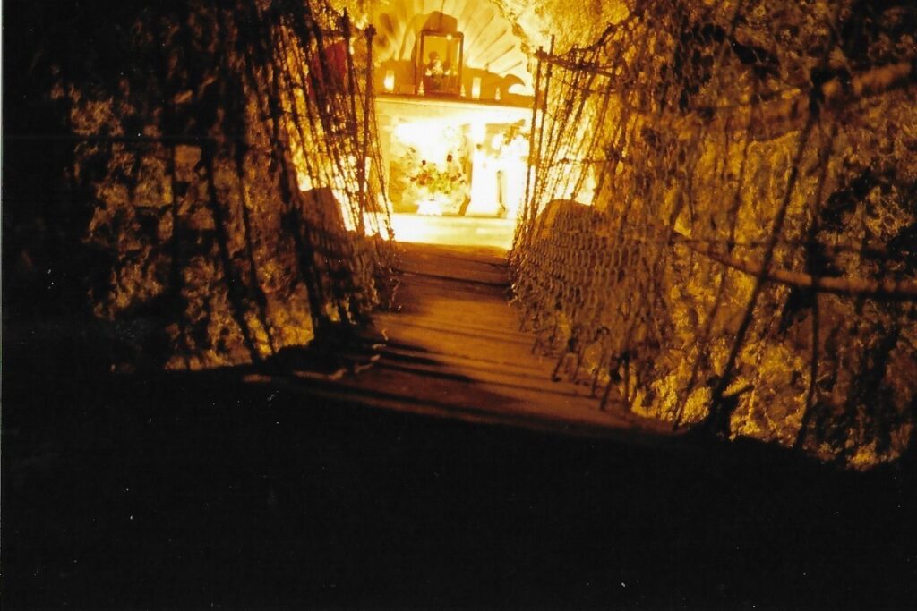 A stair case in a Zacatecas copper mine leads down to a glowing makeshift alter with religious icons.