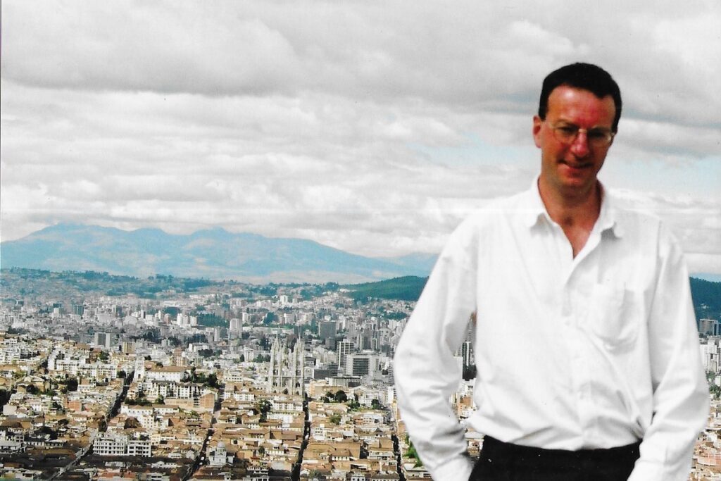 The author stands by the Virgin of Quito, with the city of Quito in the background.