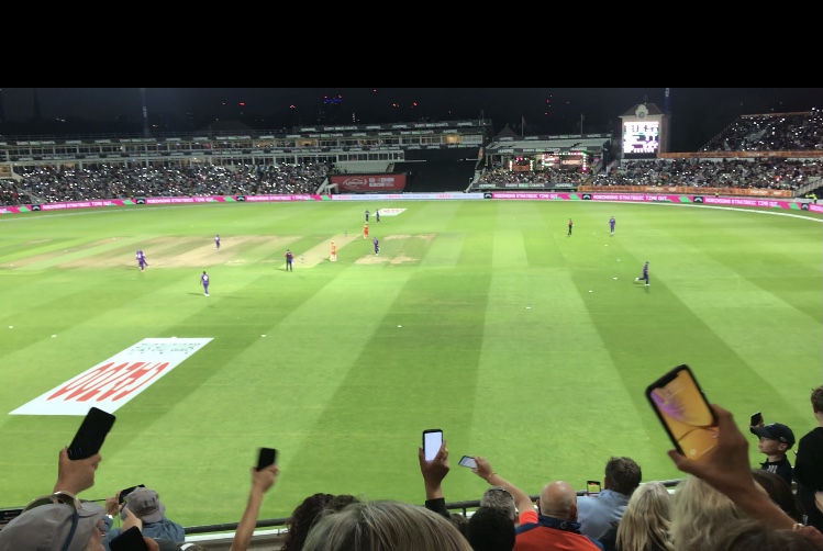 Writing about cricket. A  crowded Edgbaston watching a Hundred night match. Mobile phones with torches turned on are being waved by spectators close to the picture and around the ground, contributiing to the atmosphere.
