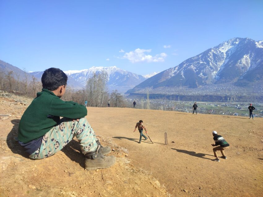 man in green hoodie walking on brown sand