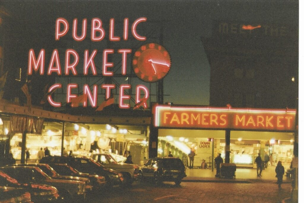 A brightly lit entrance to Seattle's Farmers Market - Huge neon signing stands above the entrance.